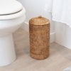 Rattan toilet paper holder with lid in white bathroom on floor by toilet 