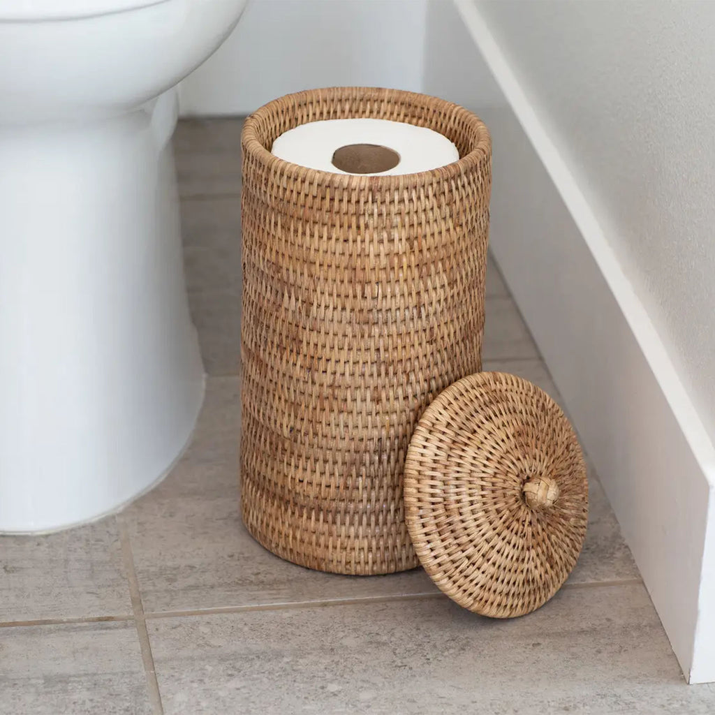 Rattan toilet paper holder with lid in white bathroom on floor by toilet