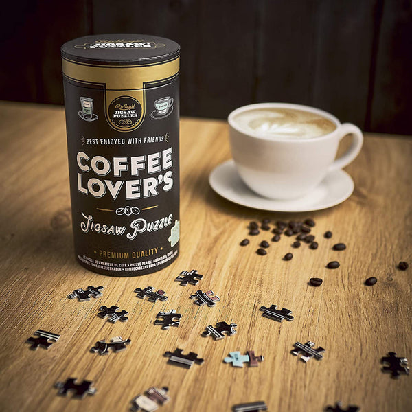 Coffee Lover's jigsaw puzzle in cardboard tube with black and white label on a table with cup of coffee