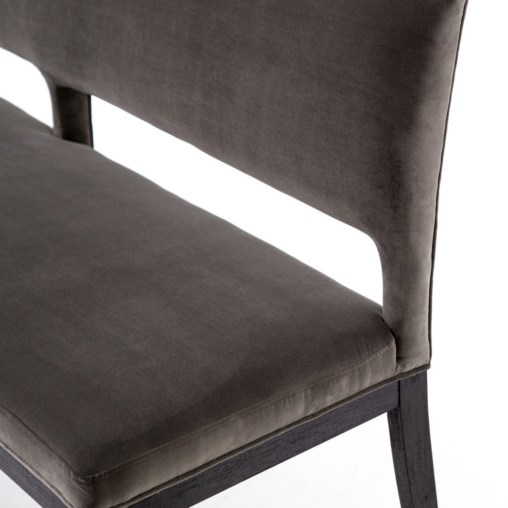 Close up of seat on Four hands furniture brand washed velvet dining bench with grey fabric seat and dark wood legs on a white background