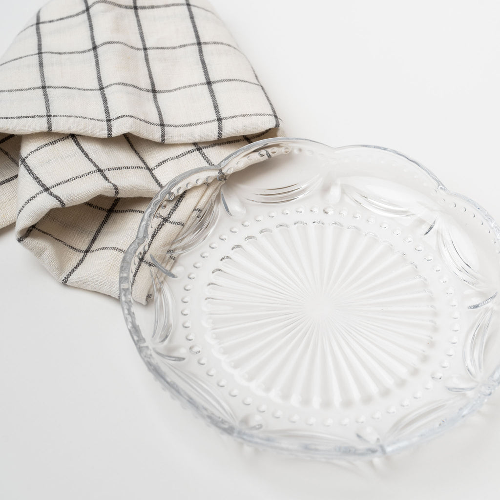 Close up of Pressed glass appetizer plate with scallop edge on a white background with linen towel