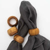 Set of four olive wood napkin rings two shown with grey linen napkins