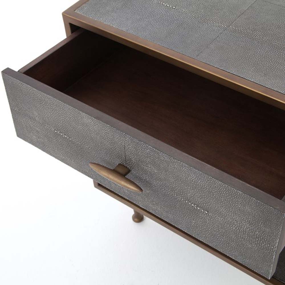 Close up of drawer on Grey shagreen nightstand with brass trim accents by four hands furniture on a white background