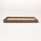 Rectangular seagrass tray with cut out handles and with linen surface on a white background