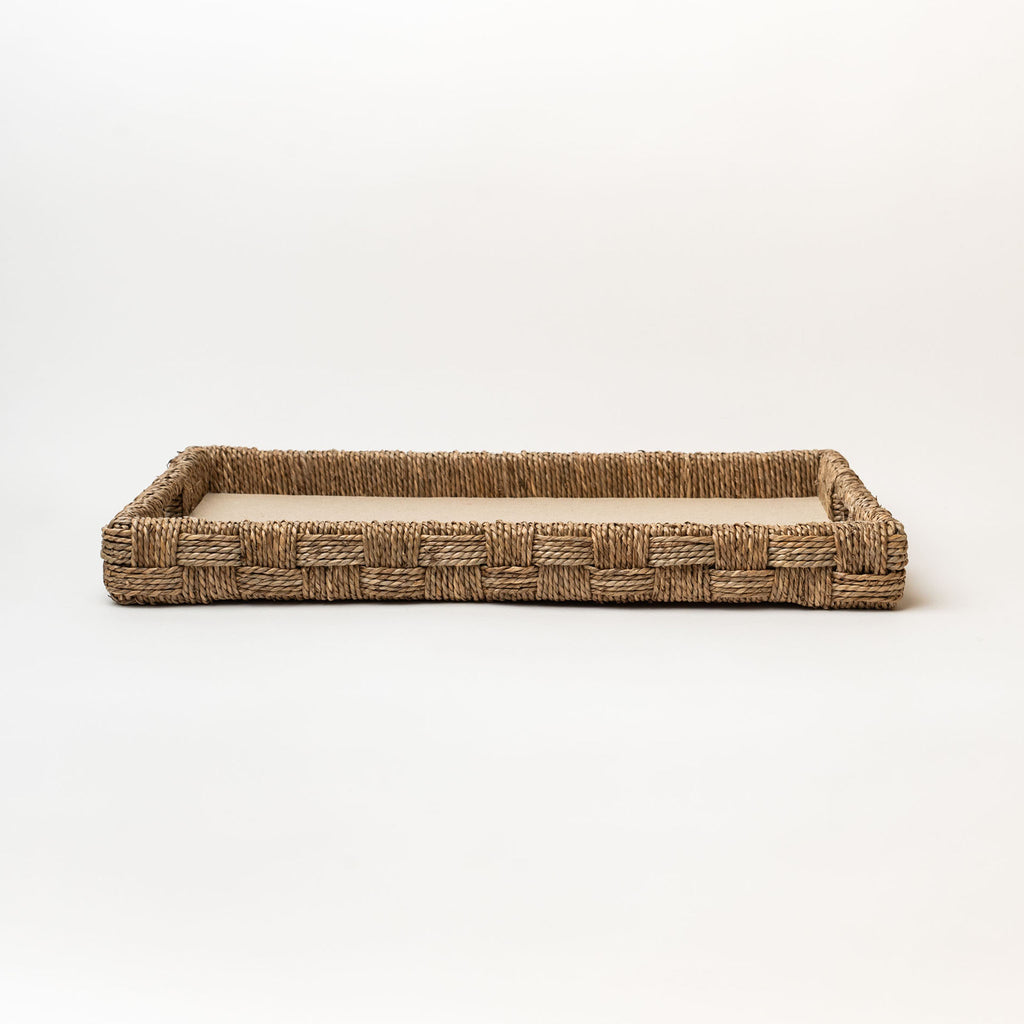 Rectangular seagrass tray with cut out handles and with linen surface on a white background