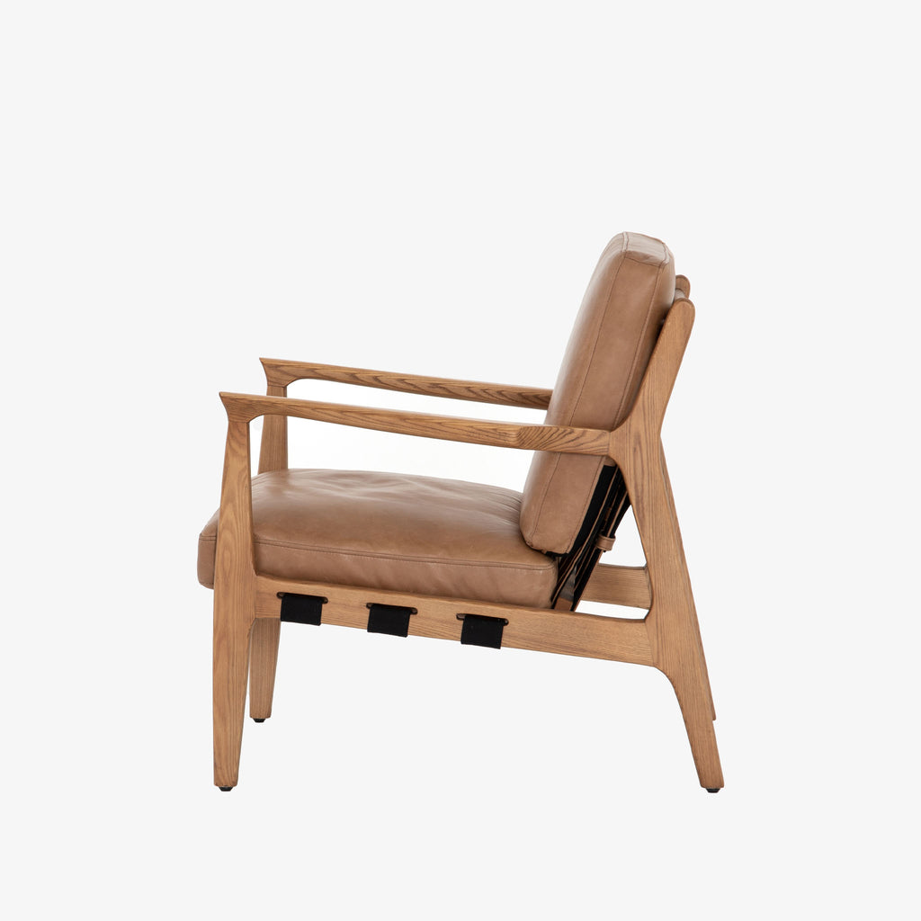 Side view of Four hands brand Silas arm chair with wood frame and patina copper leather cushions on a white background
