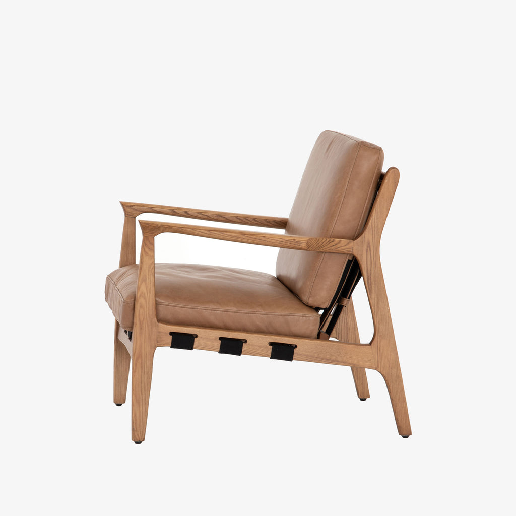 Four hands brand Silas arm chair with wood frame and patina copper leather cushions on a white background