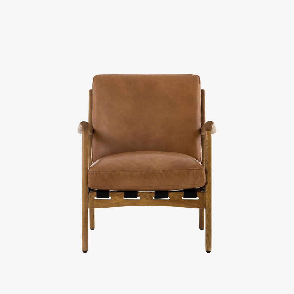 Four hands brand Silas arm chair with wood frame and patina copper leather cushions on a white background