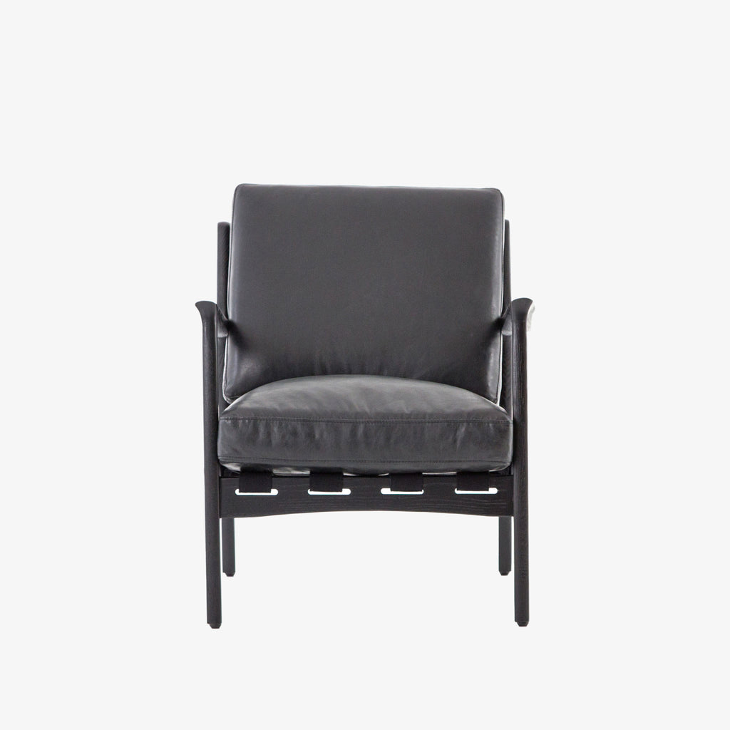 Four hands brand Silas arm chair with black wood frame and black leather cushions on a white background