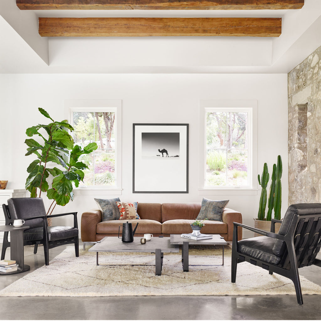 Living room space with white rug and brown leather sofa and two Four hands brand Silas arm chair with black wood frame and black leather cushions