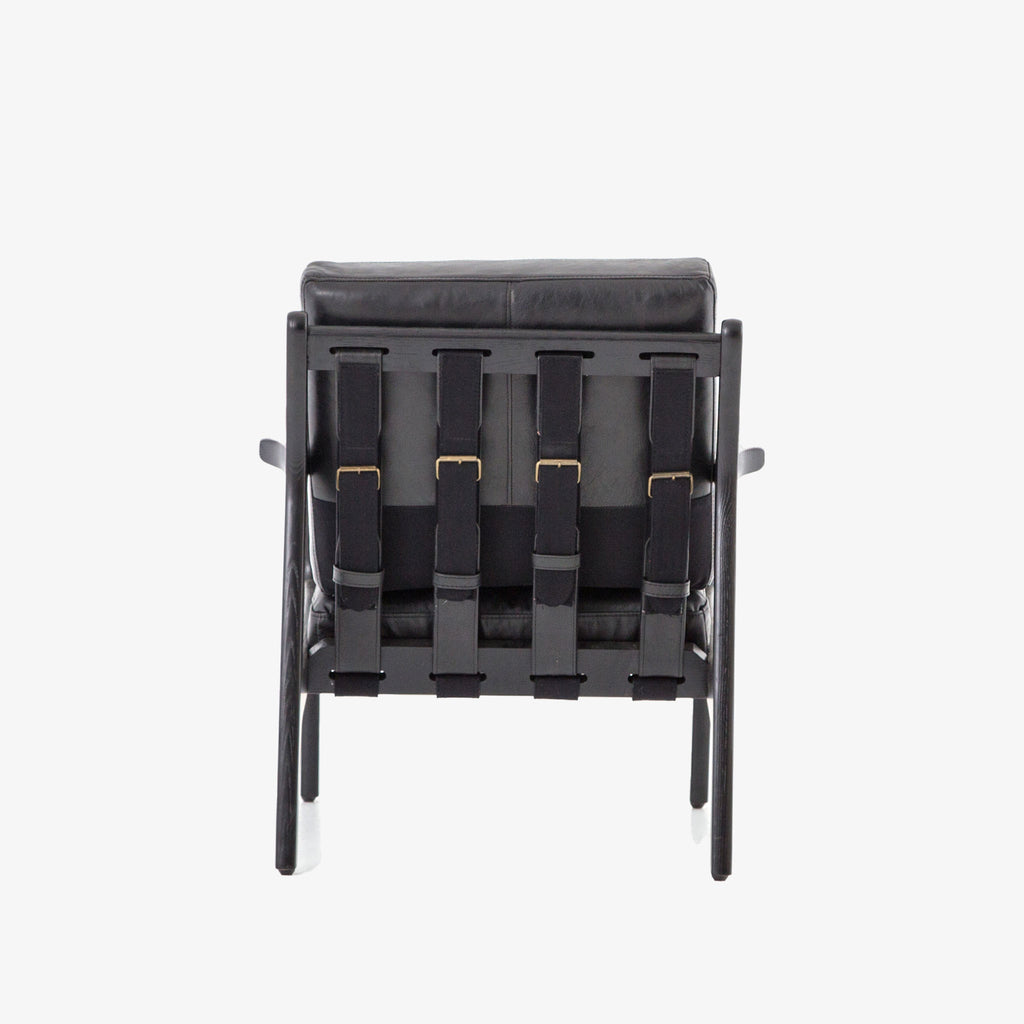 Back strapping on Four hands brand Silas arm chair with black wood frame and black leather cushions on a white background