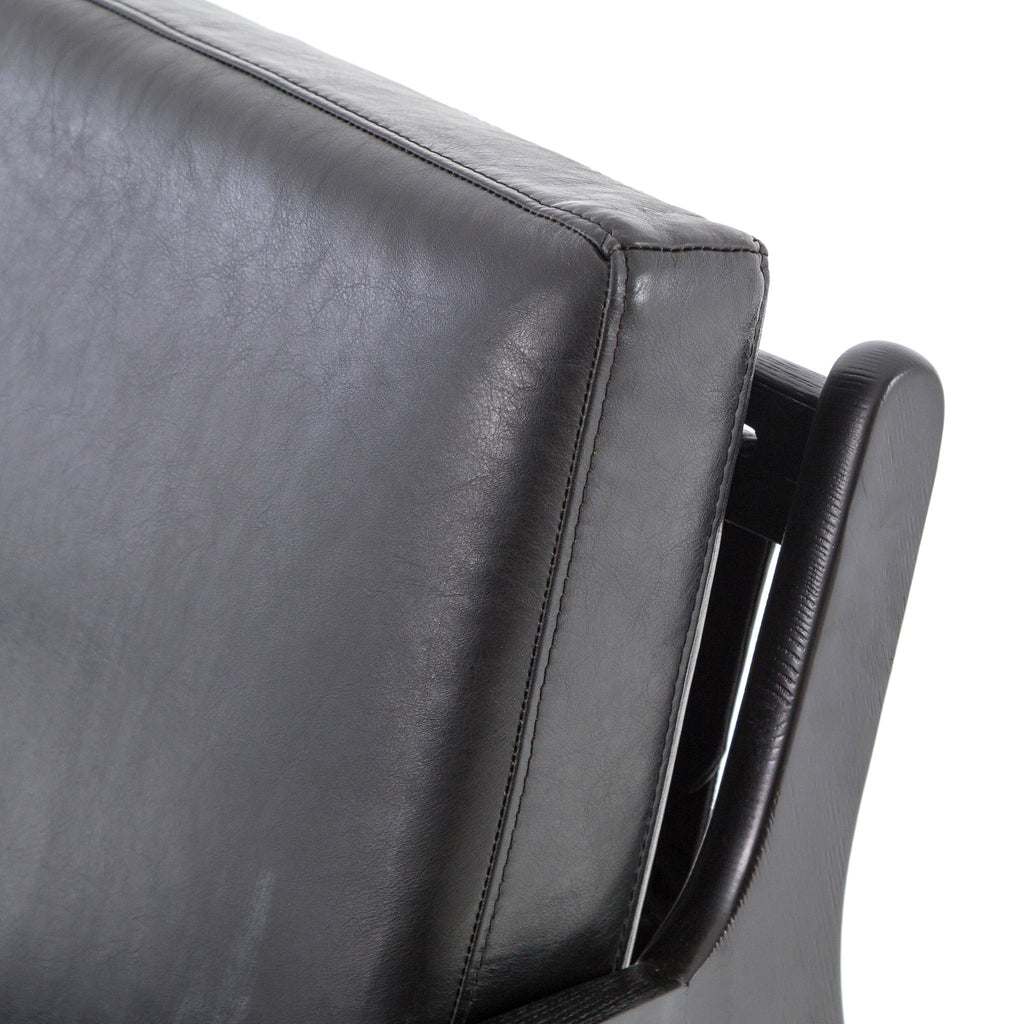 Four hands brand Silas arm chair with black wood frame and black leather cushions on a white background