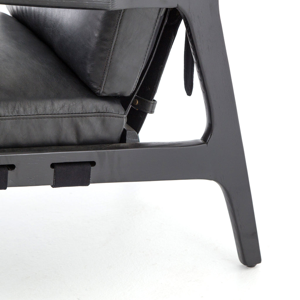 Four hands brand Silas arm chair with black wood frame and black leather cushions on a white background