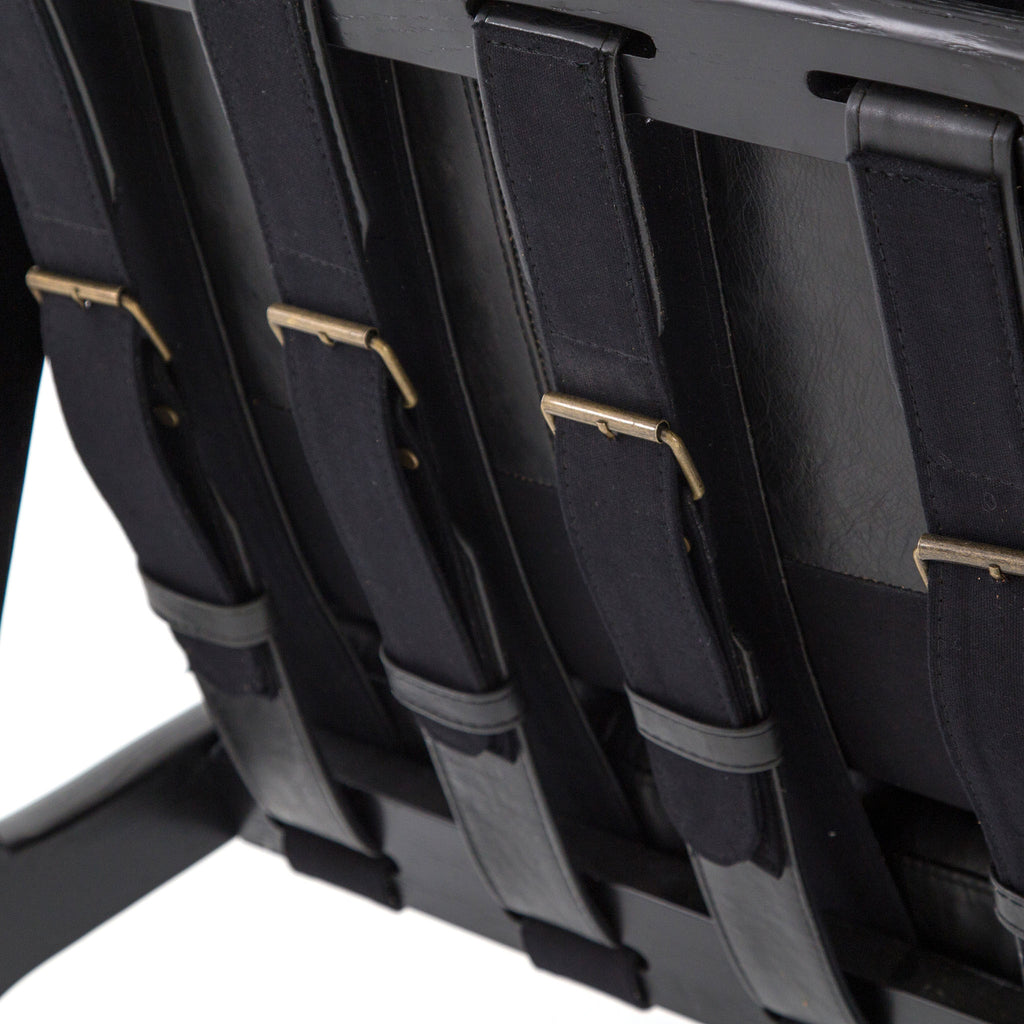 Back strapping on Four hands brand Silas arm chair with black wood frame and black leather cushions on a white background