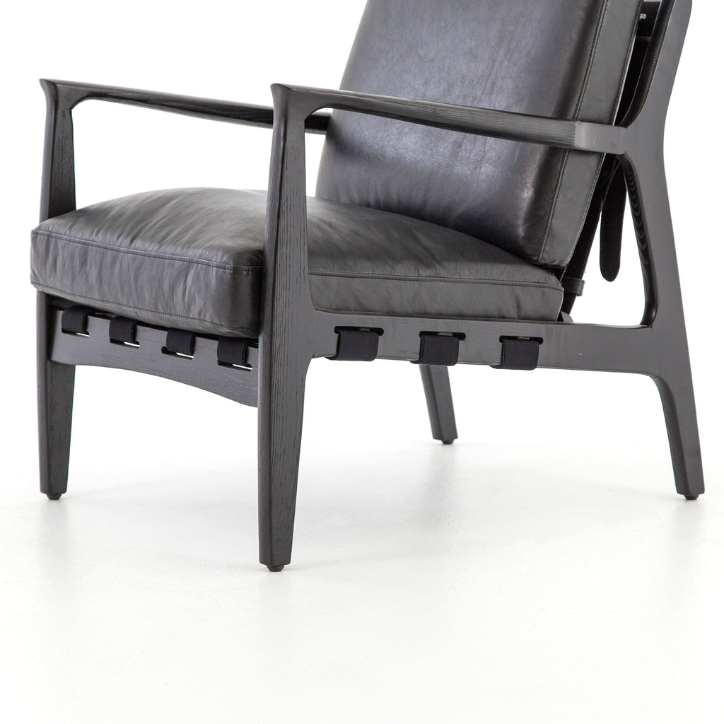 Four hands brand Silas arm chair with black wood frame and black leather cushions on a white background