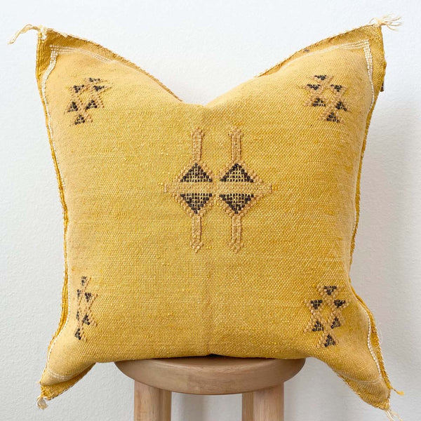 Sabra silk moroccan embroidered pillow in yellow on a stool with a white background