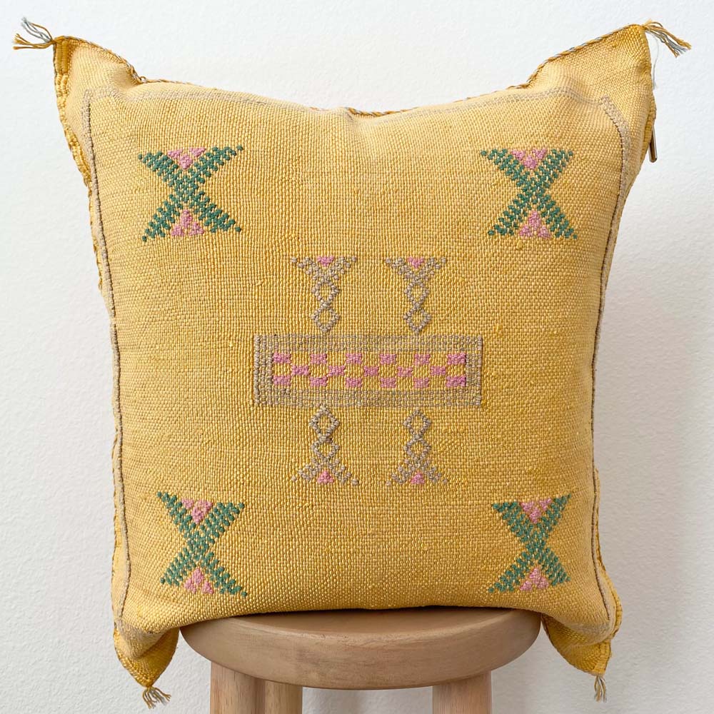 Sabra silk moroccan embroidered pillow in yellow on a stool with a white background  Edit alt text