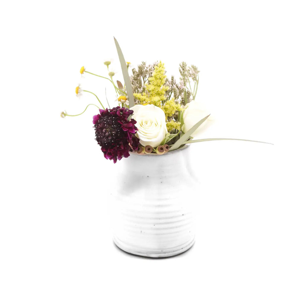 Small white ceramic vase with flowers on a white background
