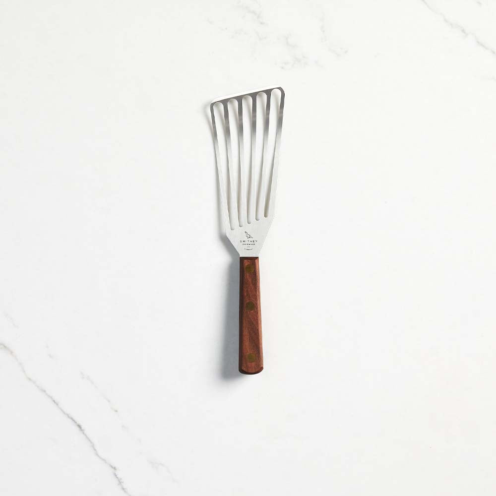 Smithey Spatula with slotted stainless steel and walnut handle on a white marble counter