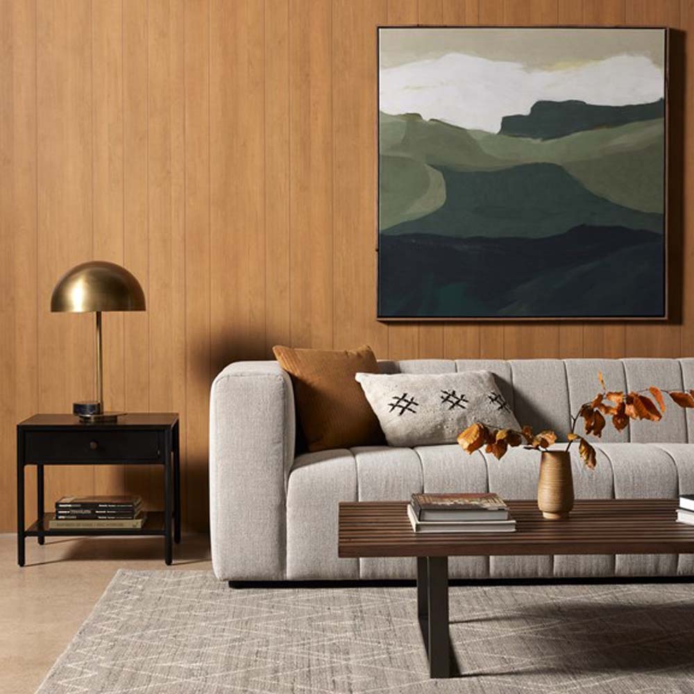 Living room with wood paneled walls beige sofa and black single drawer 'Soto' end table by four hands furniture