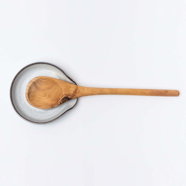 White handmade in Vermont spoon rest with olive wood spoon on a white background