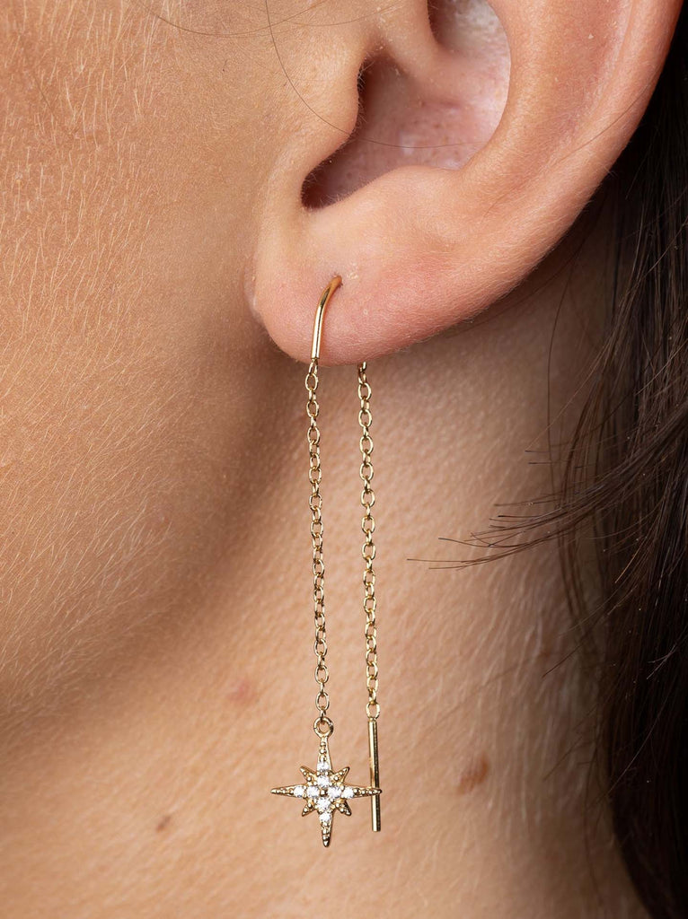 Model wearing Scream Pretty brand starburst threader earrings in silver 