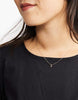 Model wearing Able brand Stella drop necklace on a black sweater