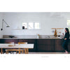 Photograph of a barefoot woman in a white and wood kitchen from the book: Still the slow home