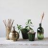 Two green planters with hobnail pattern on a wood surface with brass container and bottle 