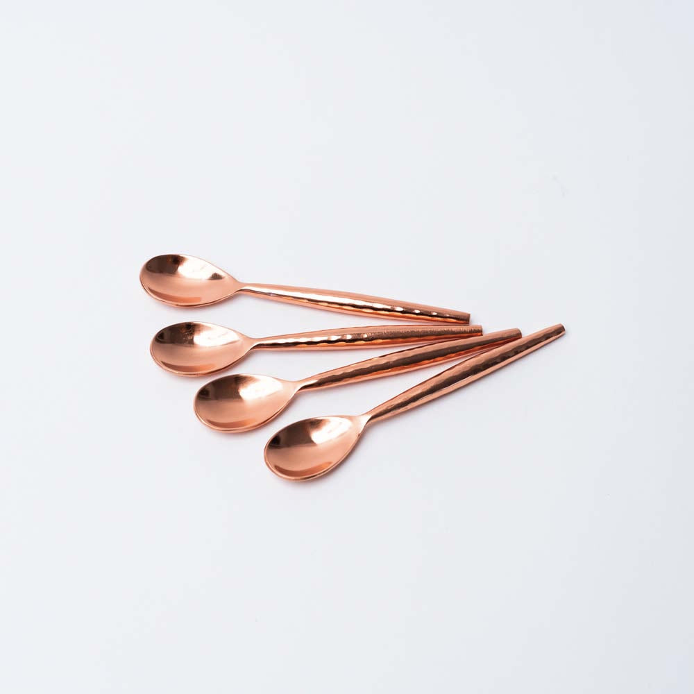 Set of four copper spoons on a white background