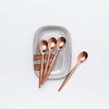 Set of four copper spoons on a small rectangular hand painted dish
