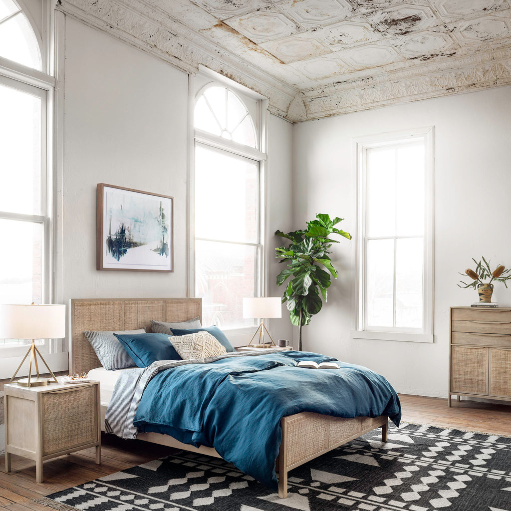 Bedroom with tin ceilings and tall windows and Natural wood and cane 'Sydney' bed by Four hands furniture on a black and white geometric rug