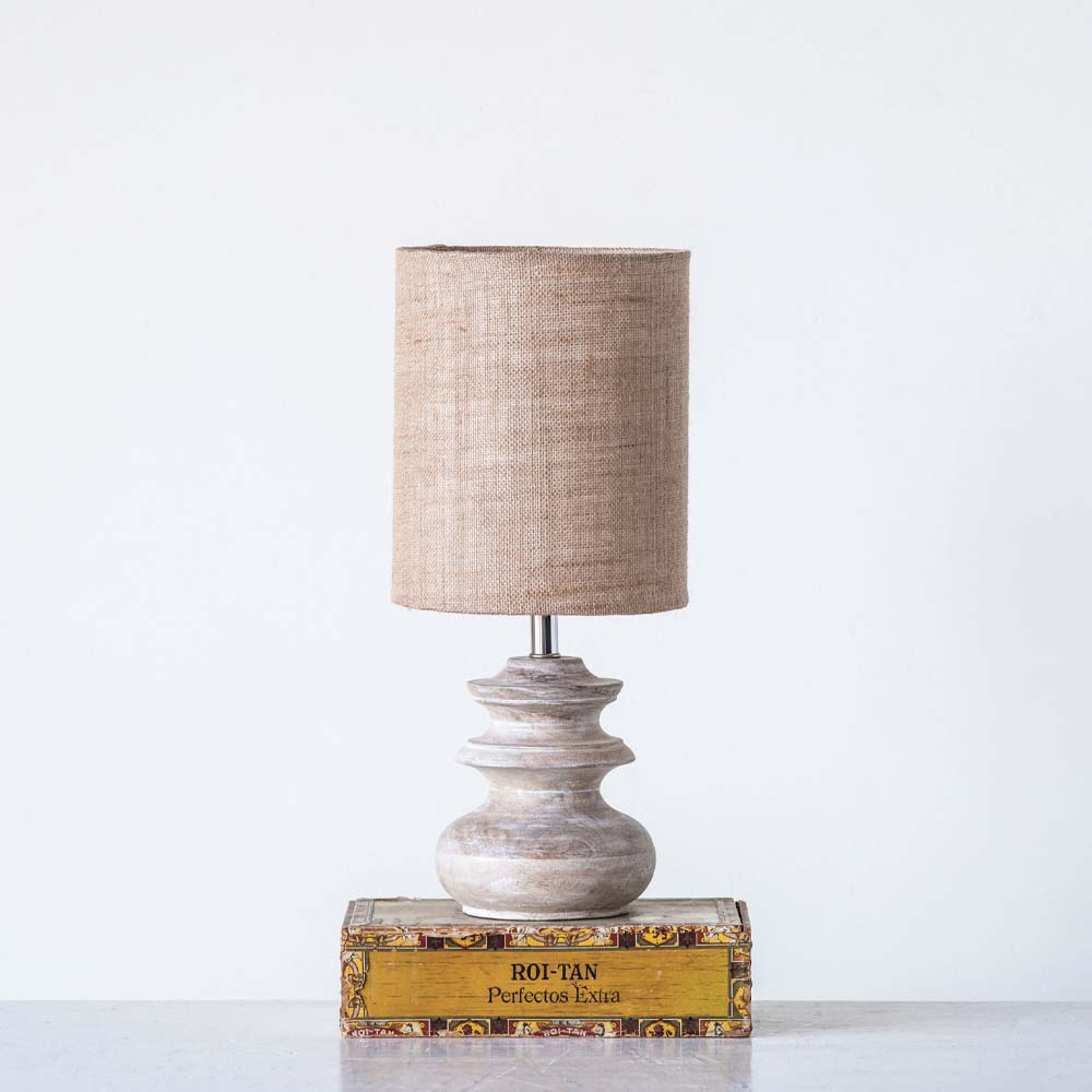 Small whitewashed lamp with jute shade on a book on white surface