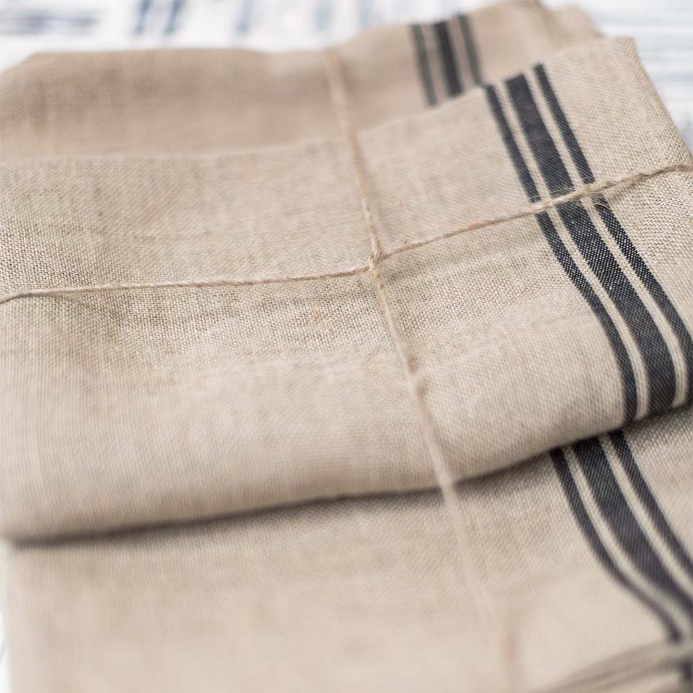 Close up of Set of two natural with black stripe Thieffry Belgian Linen kitchen tea towels on a tied with a bow 