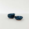 Small indigo handmade pottery bowls stacked on a white background