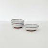 Small white handmade pottery bowls stacked on a white background