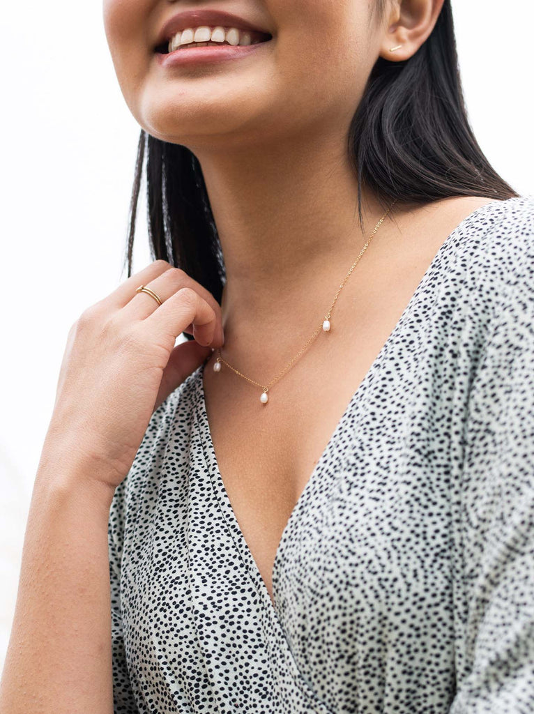 Able brand triple pearl gold necklace on a  model with blue and white top 