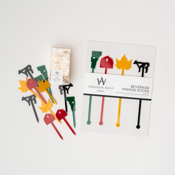Acrylic cocktail sticks in vermont state theme with green state red barn gold leaf and black cow on a white background