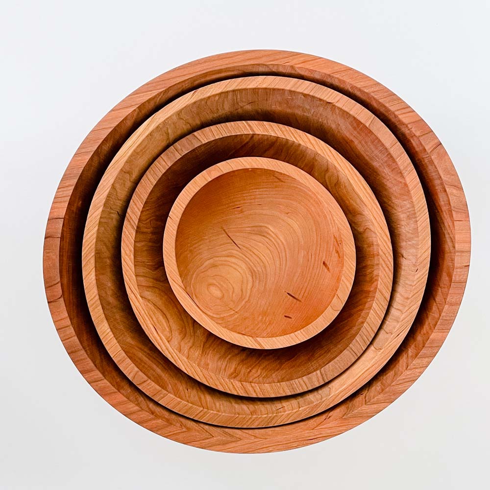 Four cherry salad bowls nested together on a white background 