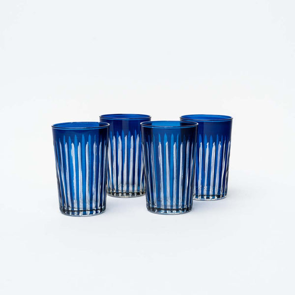 Set of four cobalt blue tea glasses with hand carved indentation on a white background