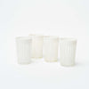 Set of four hand carved white tea glasses on a white background