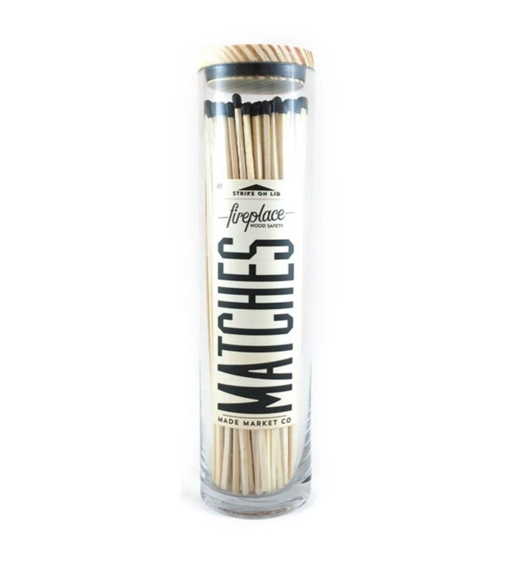 Black tip fireplace matches in glass container with wood top on white background