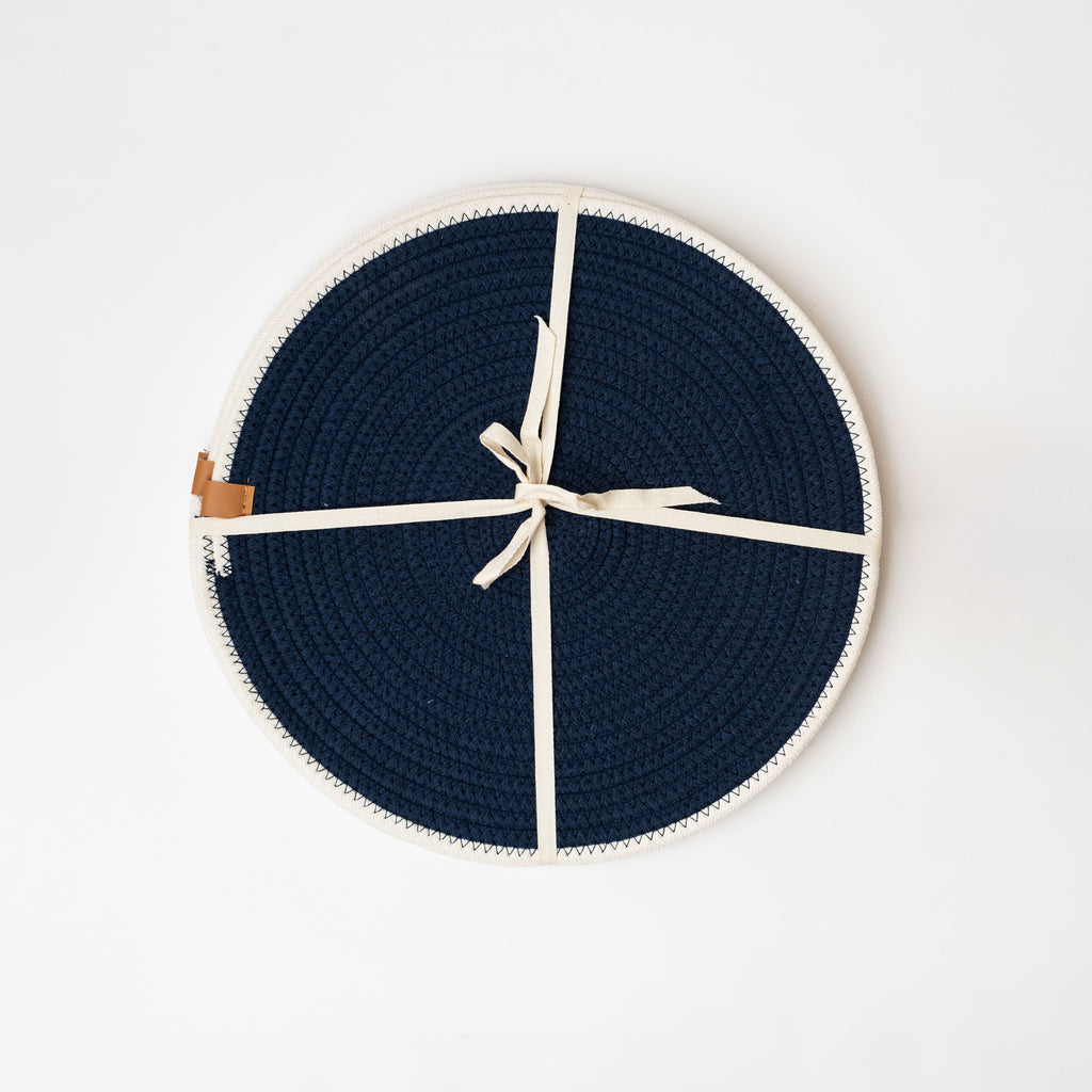 Set of four navy woven round placemats with white border