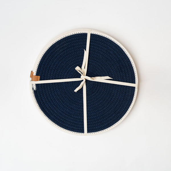 Set of four navy woven round placemats with white border