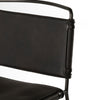 Close up view of Four hands brand wharton chair with black iron frame and black leather seat on a white background