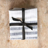 Set of three natural and black stripe tea towels tied with black ribbon on wood counter