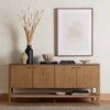 Wood four door 'Zuma' sideboard with shelf underneath by four hands furniture in a room with wood floor and cream walls 
