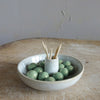 Stoneware holder with olives and tool picks on a wood surface